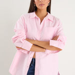 model wears a pink oversized shirt with blue jeans