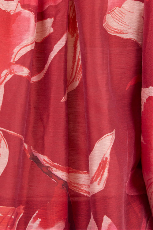 A close-up of a red floral print fabric with large pink and white flower motifs.