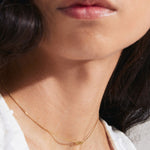 model wearing gold necklace with a pendant reading "sister"