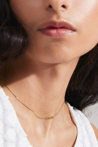 model wearing gold necklace with a pendant reading "sister"