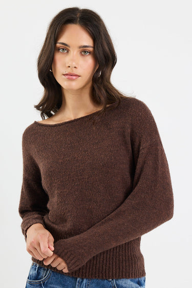 Woman wearing a brown sweater and blue jeans on a white background