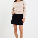 Woman wearing a beige sweater and black skirt on a white background