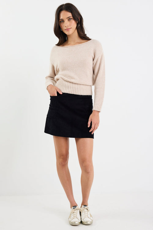 Woman wearing a beige sweater and black skirt on a white background