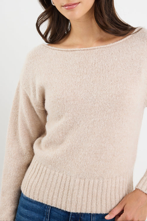 Woman wearing a beige sweater against a white background
