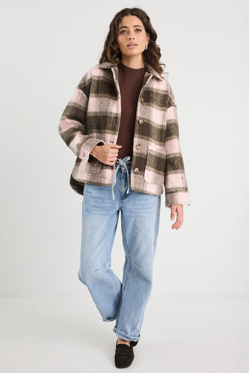 Woman wearing a plaid jacket and jeans on a white background