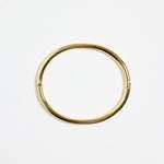 minimalist gold-plated bangle with polished finish and subtle clasp, photographed flat on a white background
