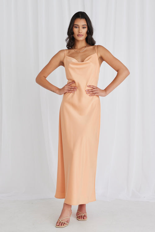 Model posing in orange satin maxi dress and heels