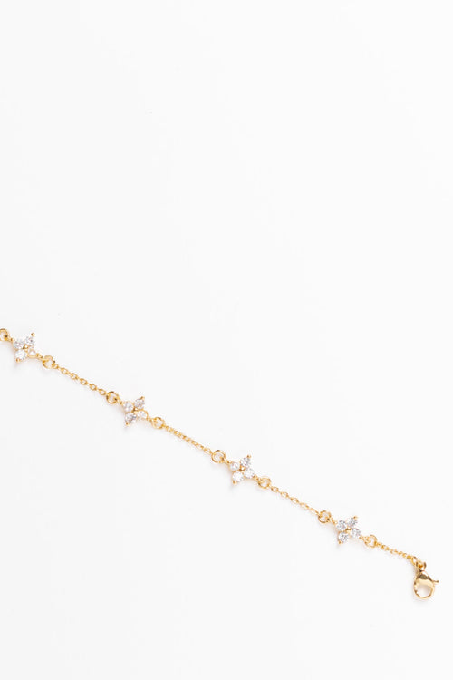 Gold bracelet with small diamond-like stones on a white background