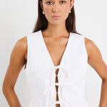 White sleeveless vest top with tie-up front detail, made from structured ramie, styled with high-waisted blue jeans.