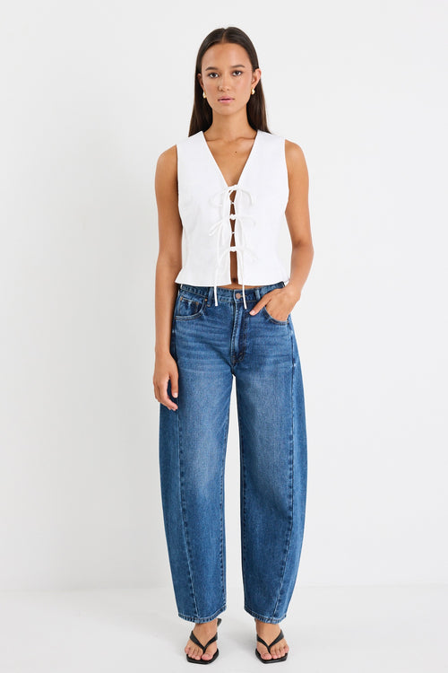 White sleeveless vest top with tie-up front detail, made from structured ramie, styled with high-waisted blue jeans.