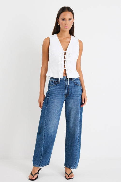 White sleeveless vest top with tie-up front detail, made from structured ramie, styled with high-waisted blue jeans.