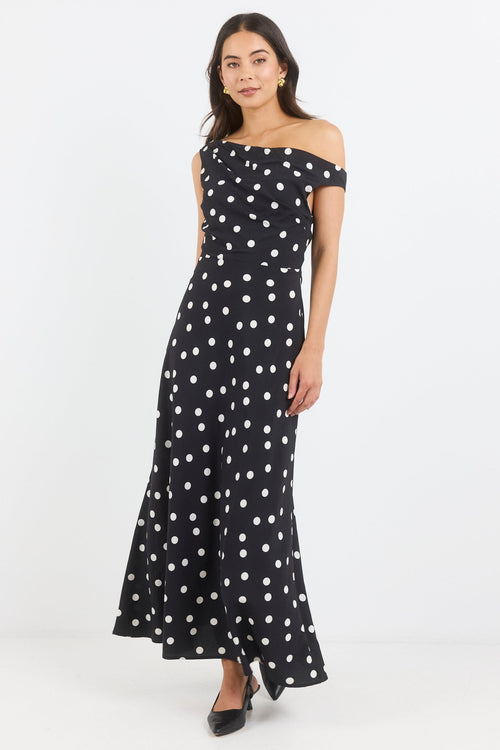 Woman wearing a black dress with white polka dots on a white background