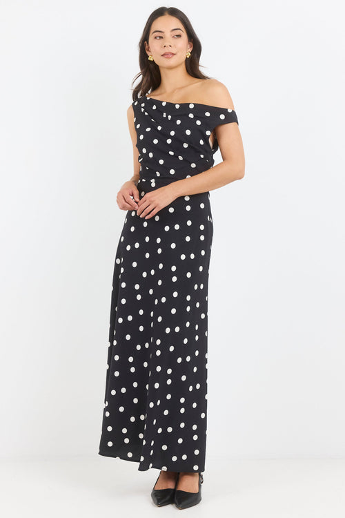 Woman wearing a black polka dot off-shoulder dress on a white background