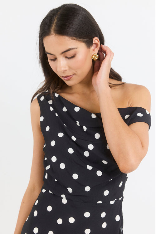 Woman wearing a black dress with white polka dots on a white background