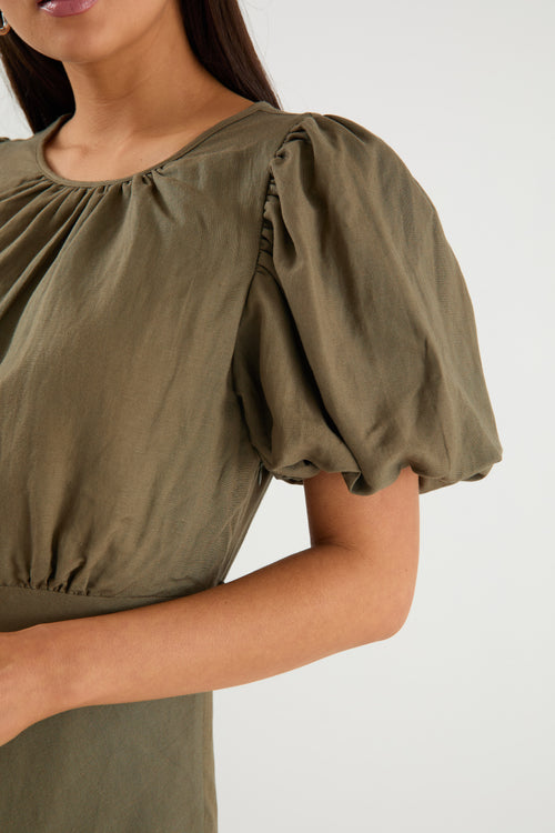 Green blouse with puff sleeves worn by a person on a white background