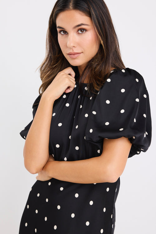 model wears a short puff sleeve black polka dot maxi dress
