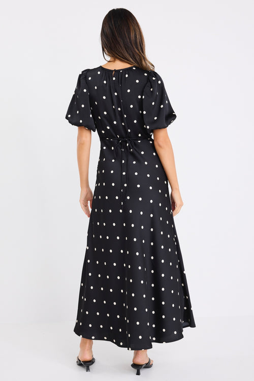 model wears a short puff sleeve black polka dot maxi dress