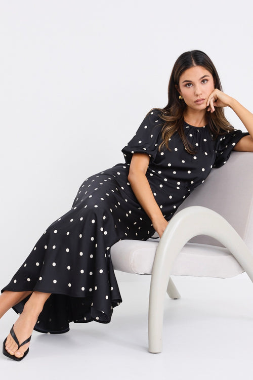 model wears a short puff sleeve black polka dot maxi dress