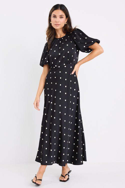 model wears a short puff sleeve black polka dot maxi dress
