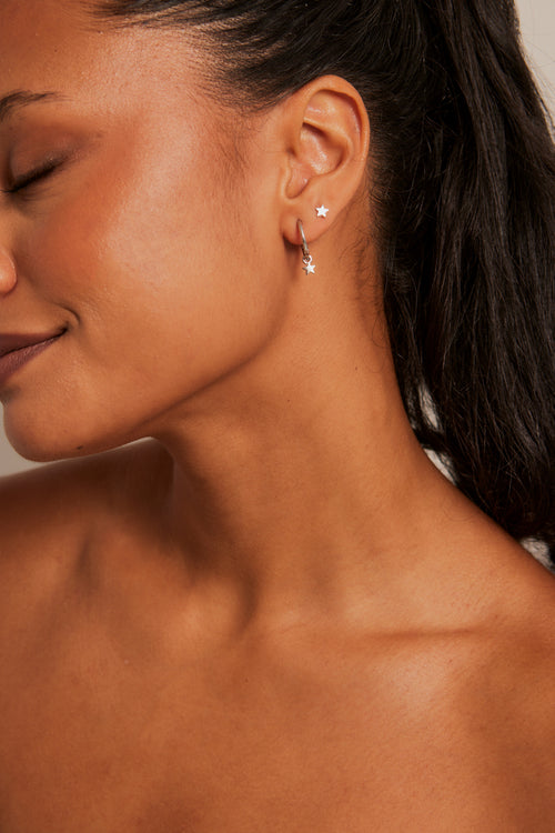 Model wears an earring with star stud and hoop. 