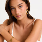 Woman wearing gold jewelry against a white background