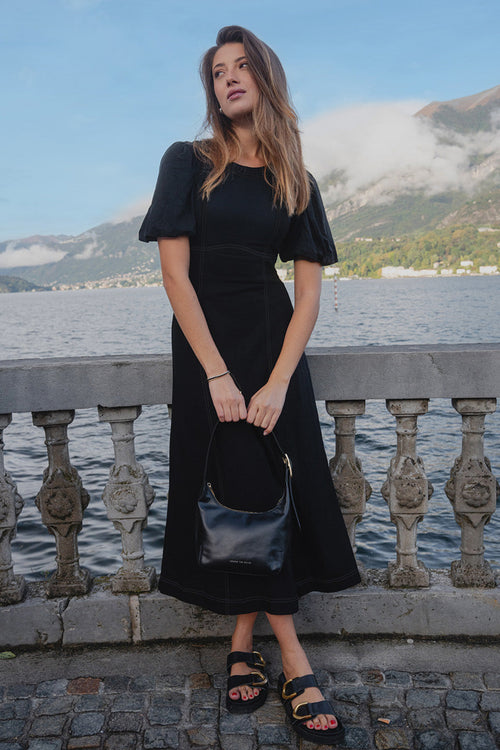 model wears a black midi dress