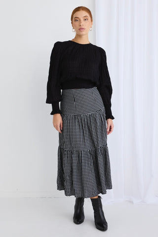 model wears a black check midi skirt