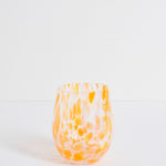 Stemless wine glass with orange and white marbled pattern on a light gray background