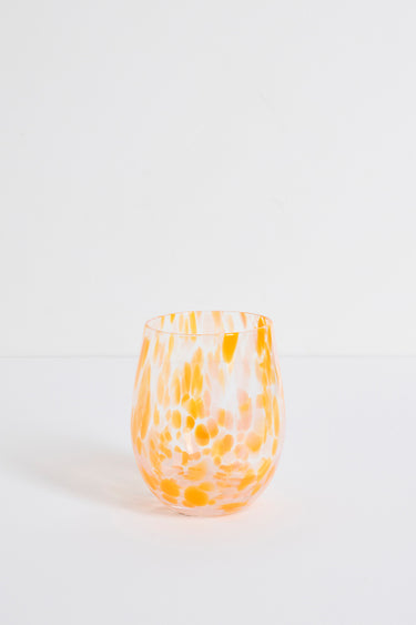 Stemless wine glass with orange and white marbled pattern on a light gray background