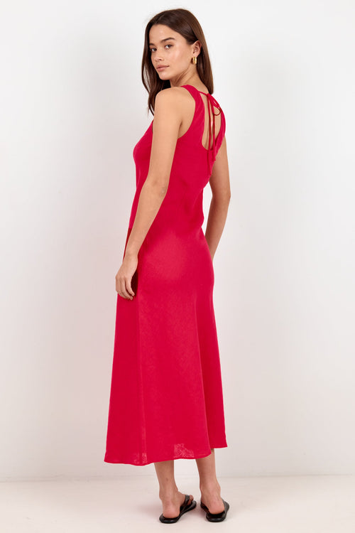 A woman modeling a bright red sleeveless maxi dress with cutout details on the back, standing against a plain white studio background.