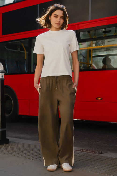 Person standing in front of a red double-decker bus on a city street.