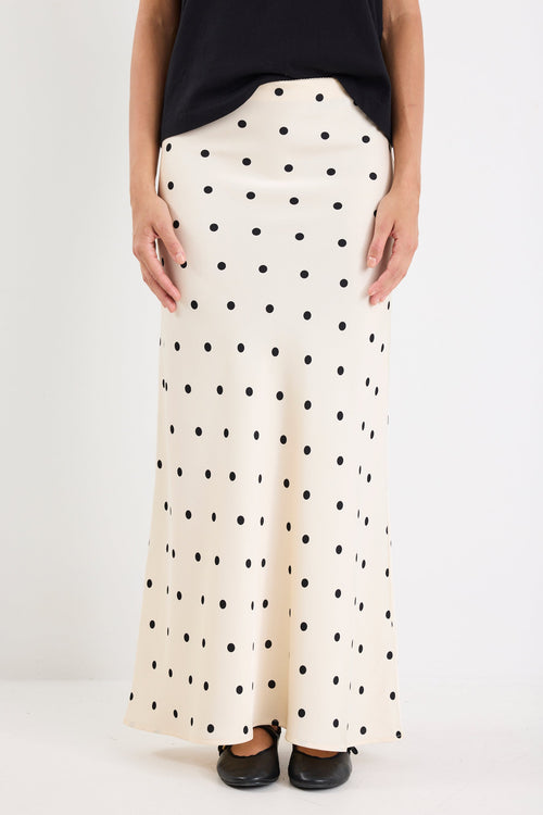 Person wearing a long polka dot skirt on a white background