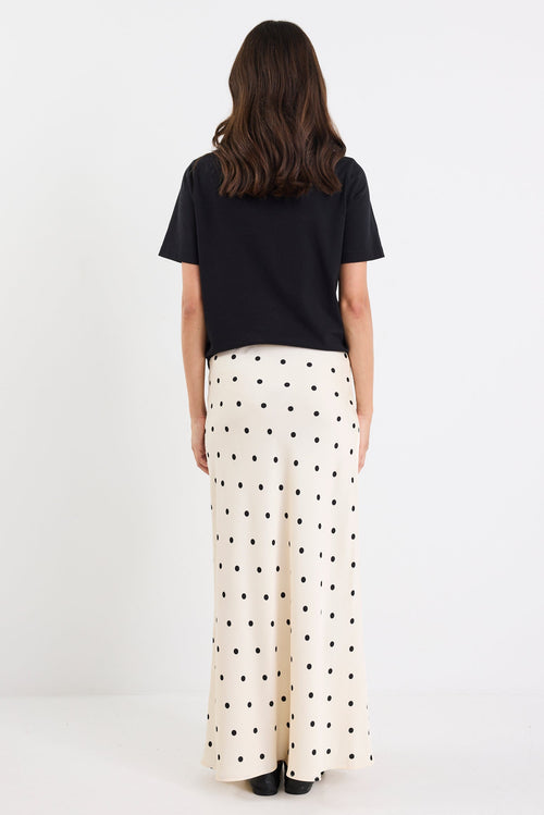 Person wearing a black top and white polka dot pants on a white background