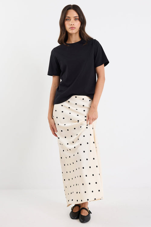 Woman wearing a black t-shirt and white polka dot skirt on a white background