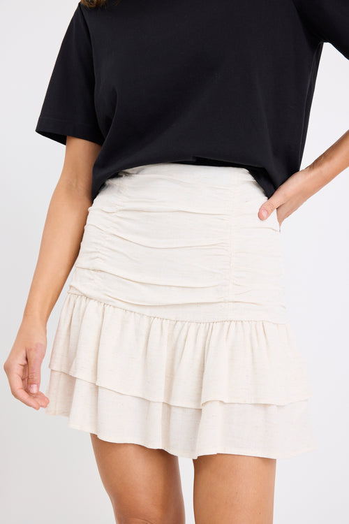 model wears a beige linen ruffle mini skirt with a black t-shirt