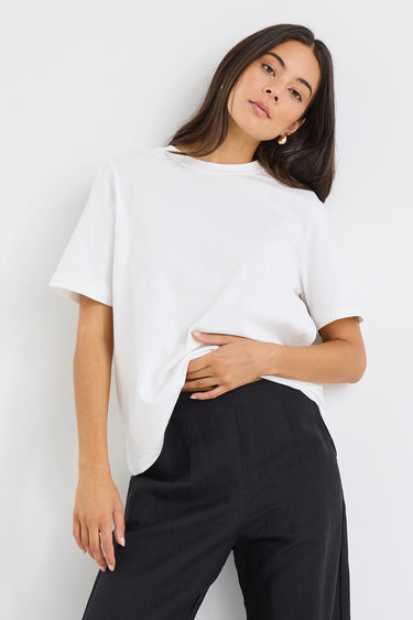 Woman wearing a relaxed-fit ivory short sleeve tee tucked into high-waisted black trousers, styled with minimal makeup and gold earrings.

@col_pattern







