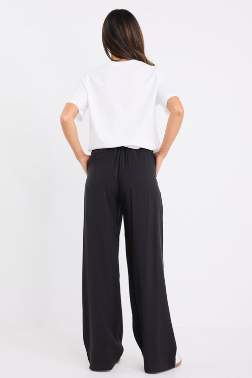 model wears black high waisted pants with a white tee