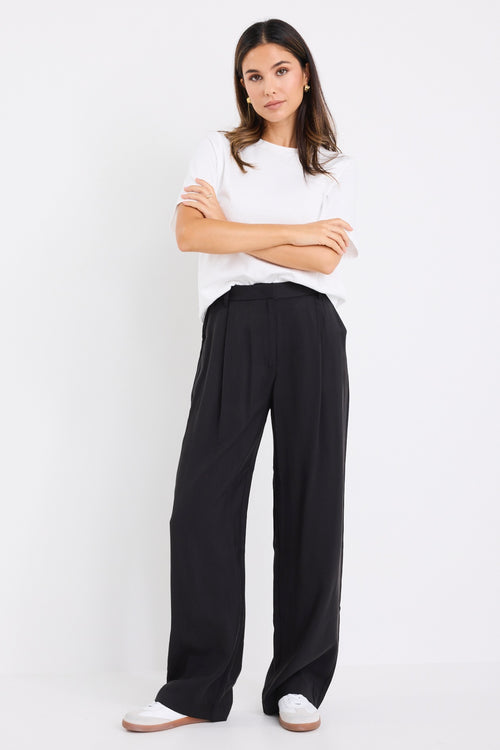 model wears black high waisted pants with a white tee