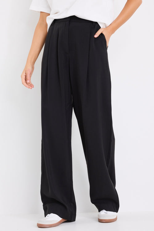 model wears black high waisted pants with a white tee