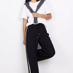 Person wearing a white shirt with a black vest and black pants with white stripes on a white background