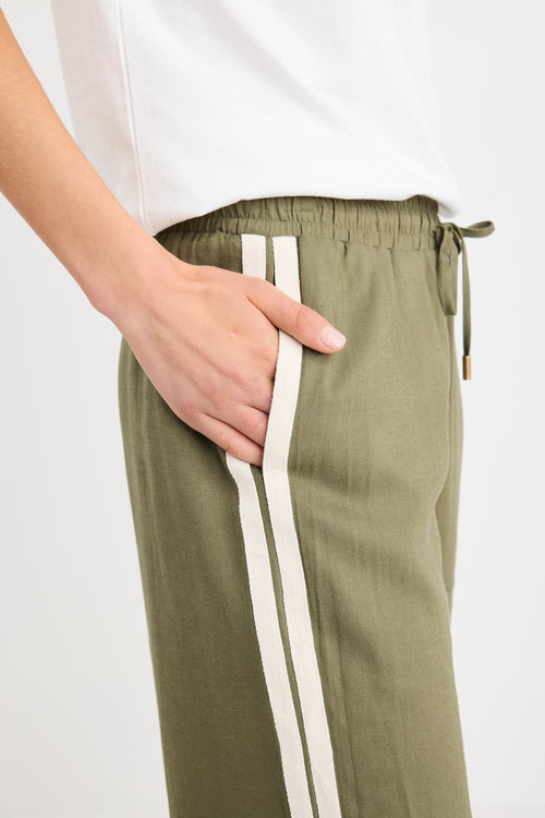 Woman wearing khaki wide-leg drawstring pants with an elastic waist, featuring a relaxed fit and side stripe detail, styled with a plain white tee and white sneakers.