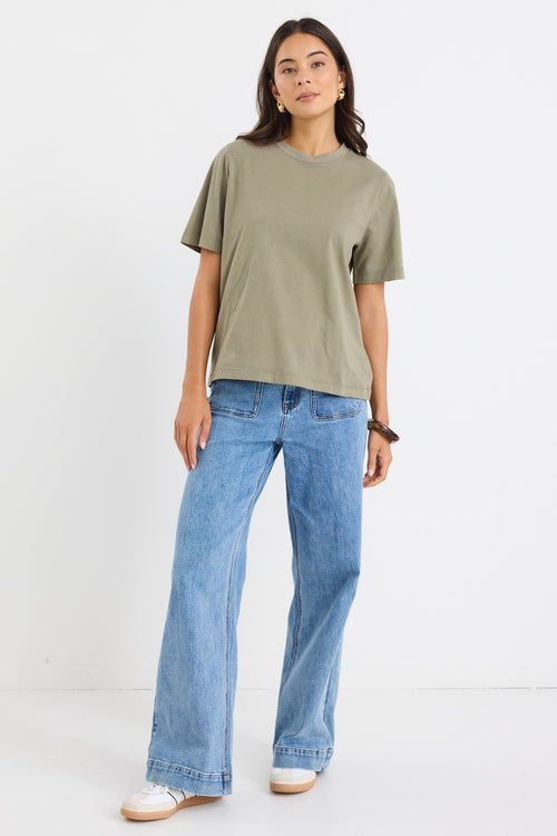 model wears a green khaki t-shirt with light blue jeans