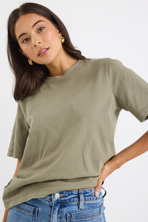 model wears a green khaki t-shirt with light blue jeans
