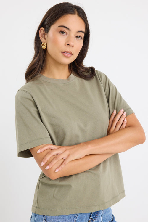 model wears a green khaki t-shirt with light blue jeans