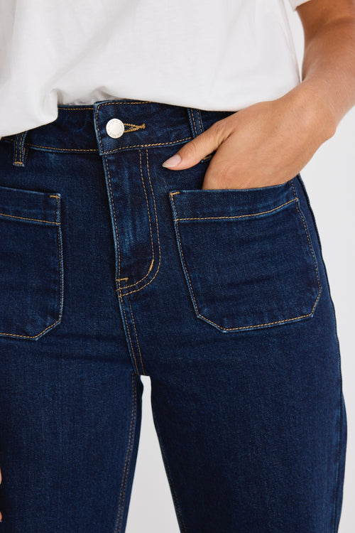 Person wearing dark blue jeans with a white background