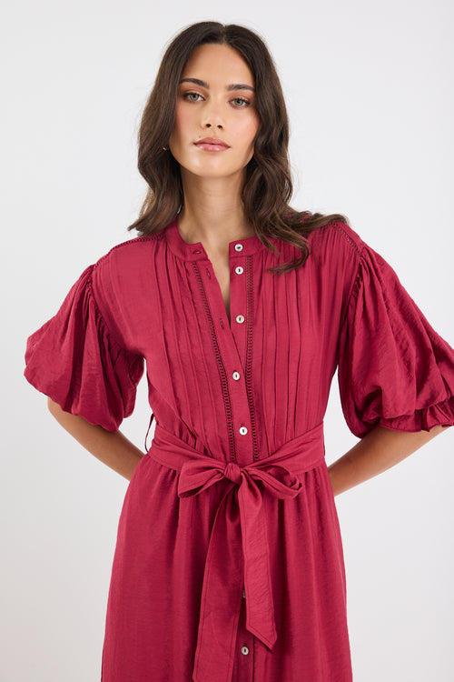 Woman wearing a red dress with puffed sleeves on a white background
