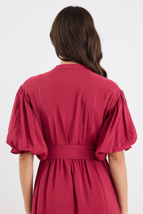 Woman wearing a red dress with puff sleeves on a white background