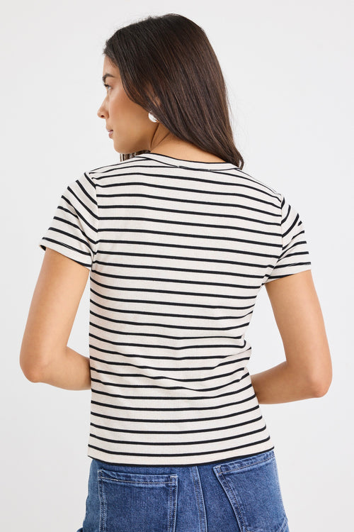 model wears a black and ecru stripe baby tee with dark blue jeans