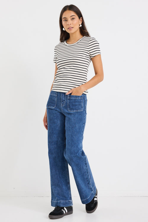 model wears a black and ecru stripe baby tee with dark blue jeans