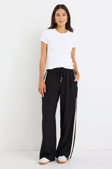 Black relaxed-fit Townie Pants with gold toggle drawstring, matte side stripe detail, and soft draped fabric, styled for a modern, transeasonal look